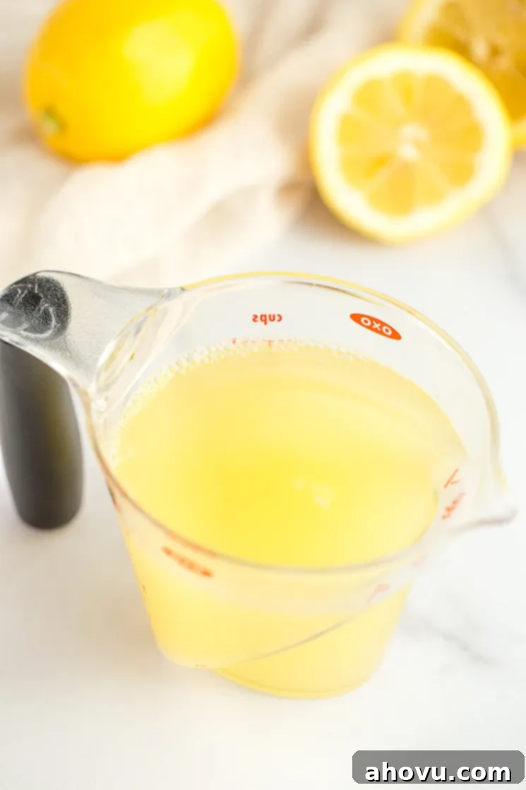 A clear measuring cup filled with fresh lemon juice.