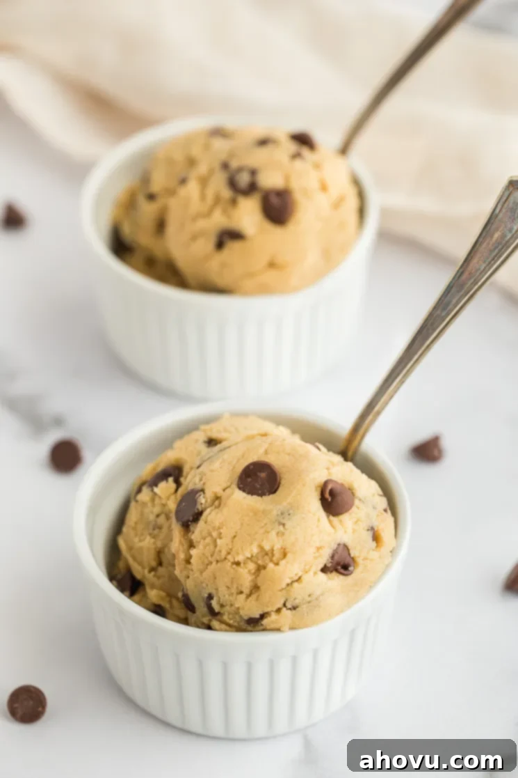 Two small white ramekins filled with irresistible edible cookie dough, each with a spoon ready for a bite.