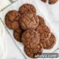 A perfectly baked, crinkly-topped brownie cookie sitting on an antique safety grater, emphasizing its rich texture and deep chocolate color.