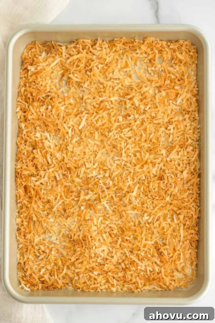 A batch of perfectly toasted coconut spread out onto a baking sheet, showcasing its even golden color.