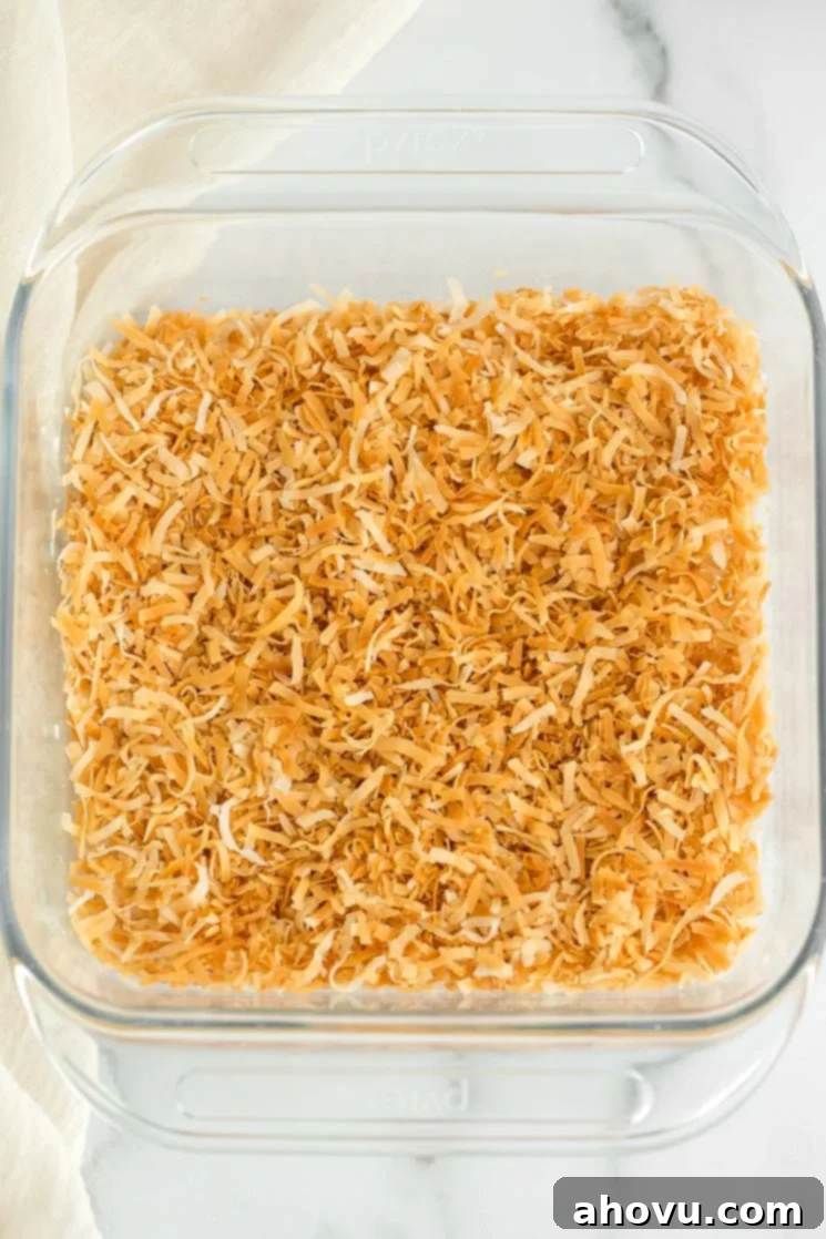 A glass baking dish with golden toasted coconut covering the bottom, ready to be used or cooled.