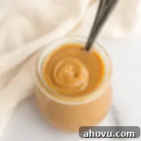 A close-up image of rich, golden-brown dulce de leche in a small glass jar, ready to be enjoyed.