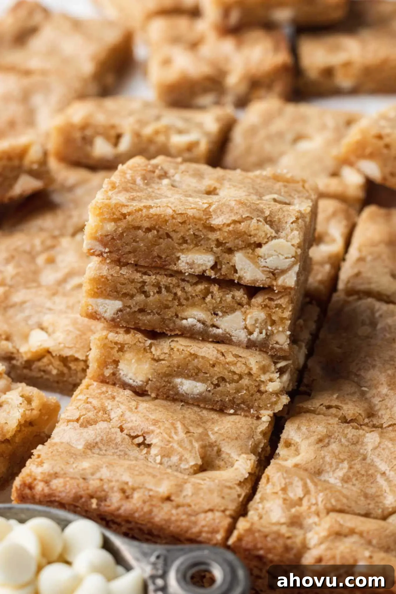 Sliced blondies with a stack of three bars piled in the foreground, showcasing their chewy texture and white chocolate chips.