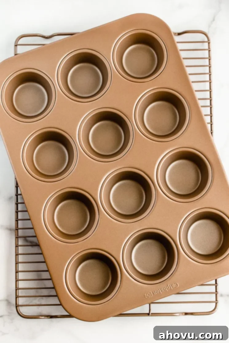A muffin pan and cooling rack stacked on top of each other on top of a marble surface, ready for baked goods.