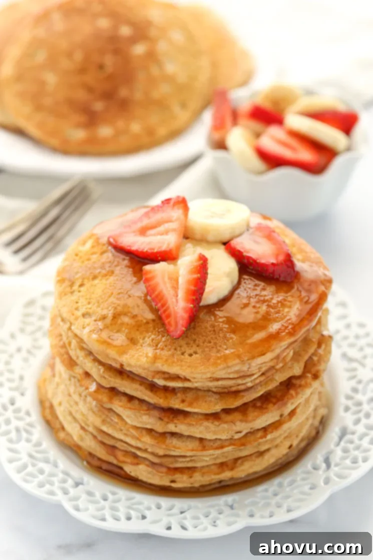 Wholesome Wheat Stacks 2 A stack of whole wheat pancakes topped with strawberry slices, banana slices, and maple syrup.