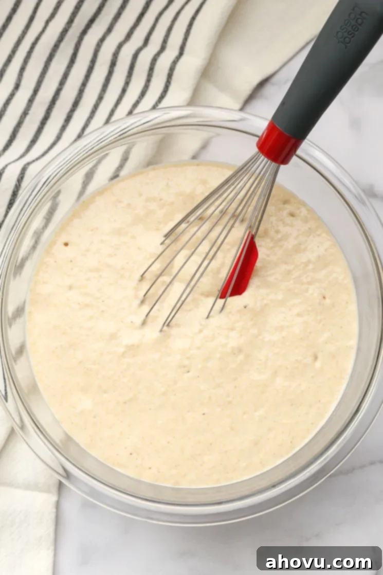 Wholesome Wheat Stacks 3 A clear bowl with pancake batter and a whisk.