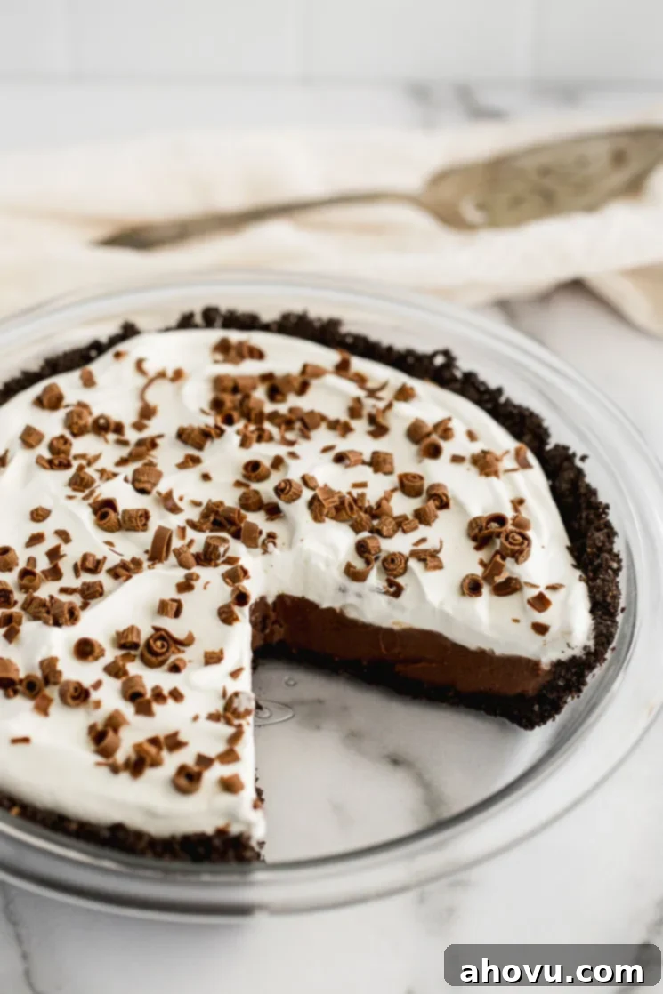 A beautiful, fully assembled chocolate cream pie with a slice carefully removed, revealing the decadent layers of crust, filling, and whipped cream.