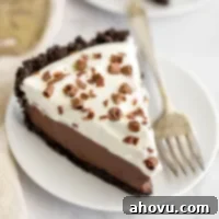 A slice of homemade chocolate cream pie on a white plate, garnished with chocolate shavings and whipped cream.