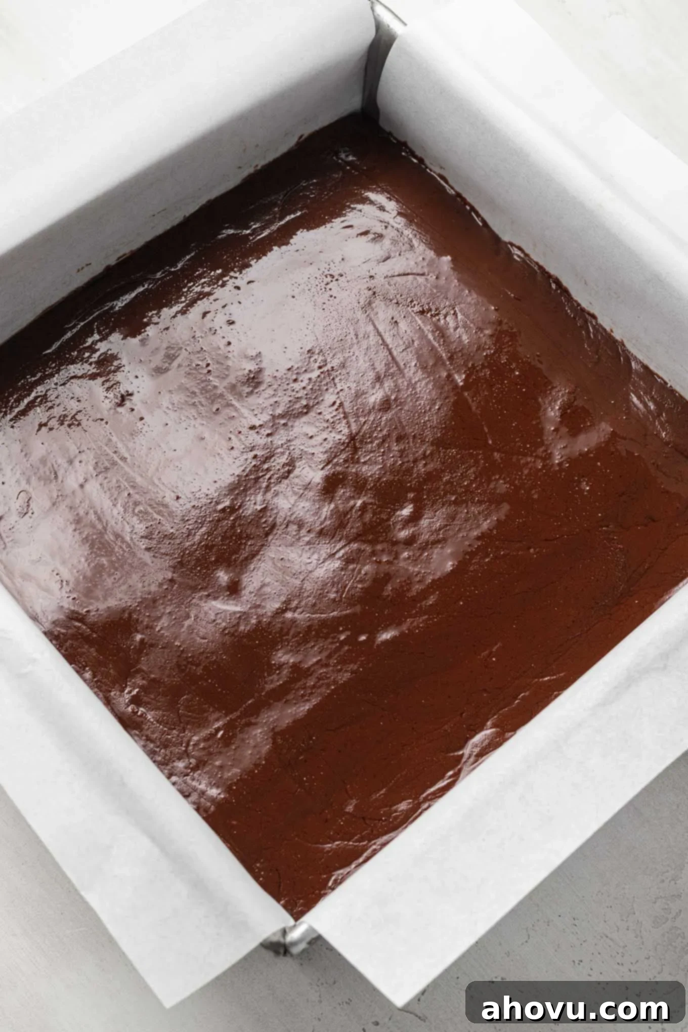 Foolproof Fudge in Minutes 4 Melted chocolate fudge in a baking pan lined with parchment paper.
