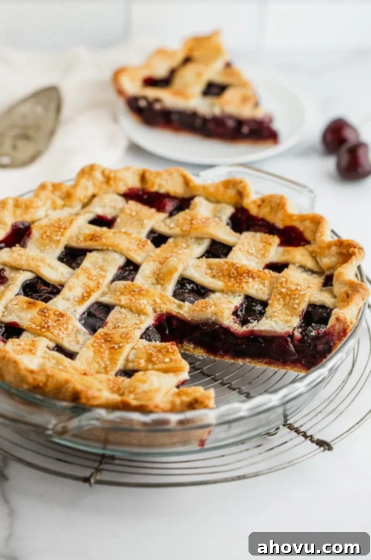 A cherry pie with one slice taken out showing the lattice crust and cherry filling. 
