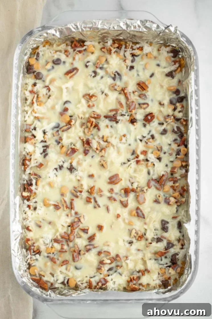 Irresistible Magic Bars 4 A 9x13 inch baking pan filled with all seven layers of ingredients for Magic Cookie Bars, ready to be baked into a delicious dessert.