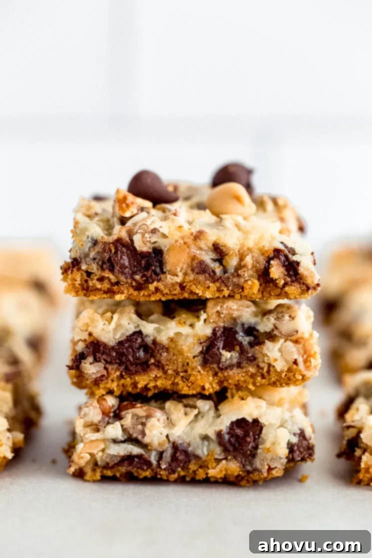 Irresistible Magic Bars 5 A stack of perfectly cut 7-layer Magic Cookie Bars presented on a piece of parchment paper, highlighting the delightful combination of textures and ingredients.