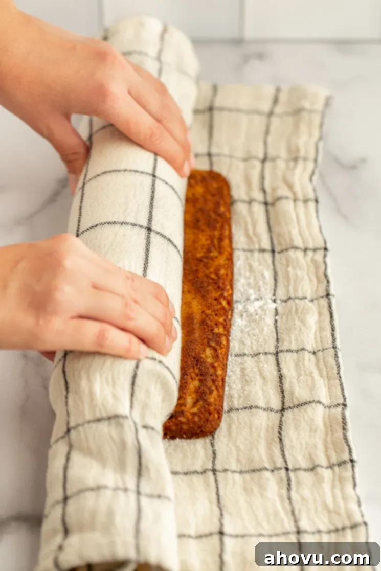 Autumn Spice Swirl 5 The process of rolling the warm pumpkin cake into a clean kitchen towel that has been dusted with powdered sugar.