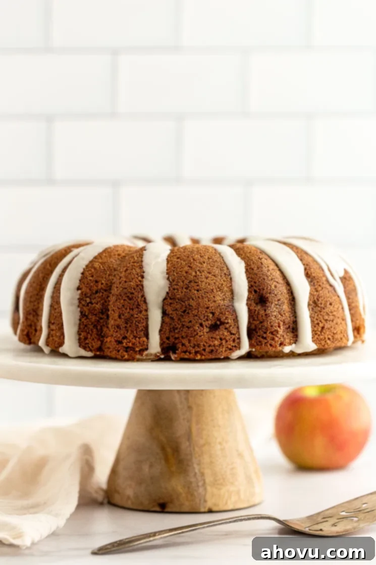 An apple cake sitting on top of a marble cake stand. A perfect fall dessert for any occasion.