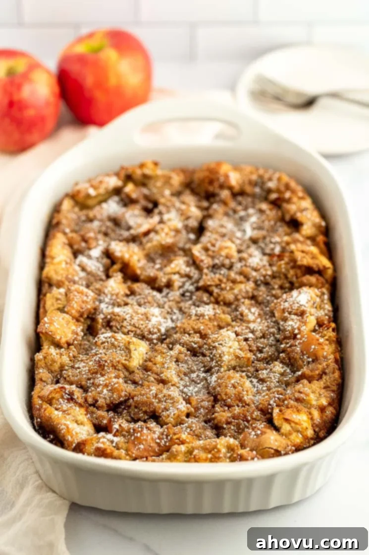 Baked apple French toast casserole in a white baking dish, dusted with powdered sugar and ready to serve for breakfast.