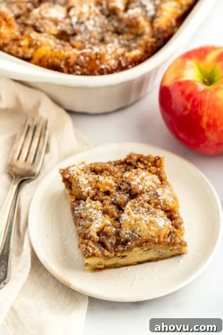 A perfect slice of apple streusel French toast casserole on a white plate, showcasing the layers.