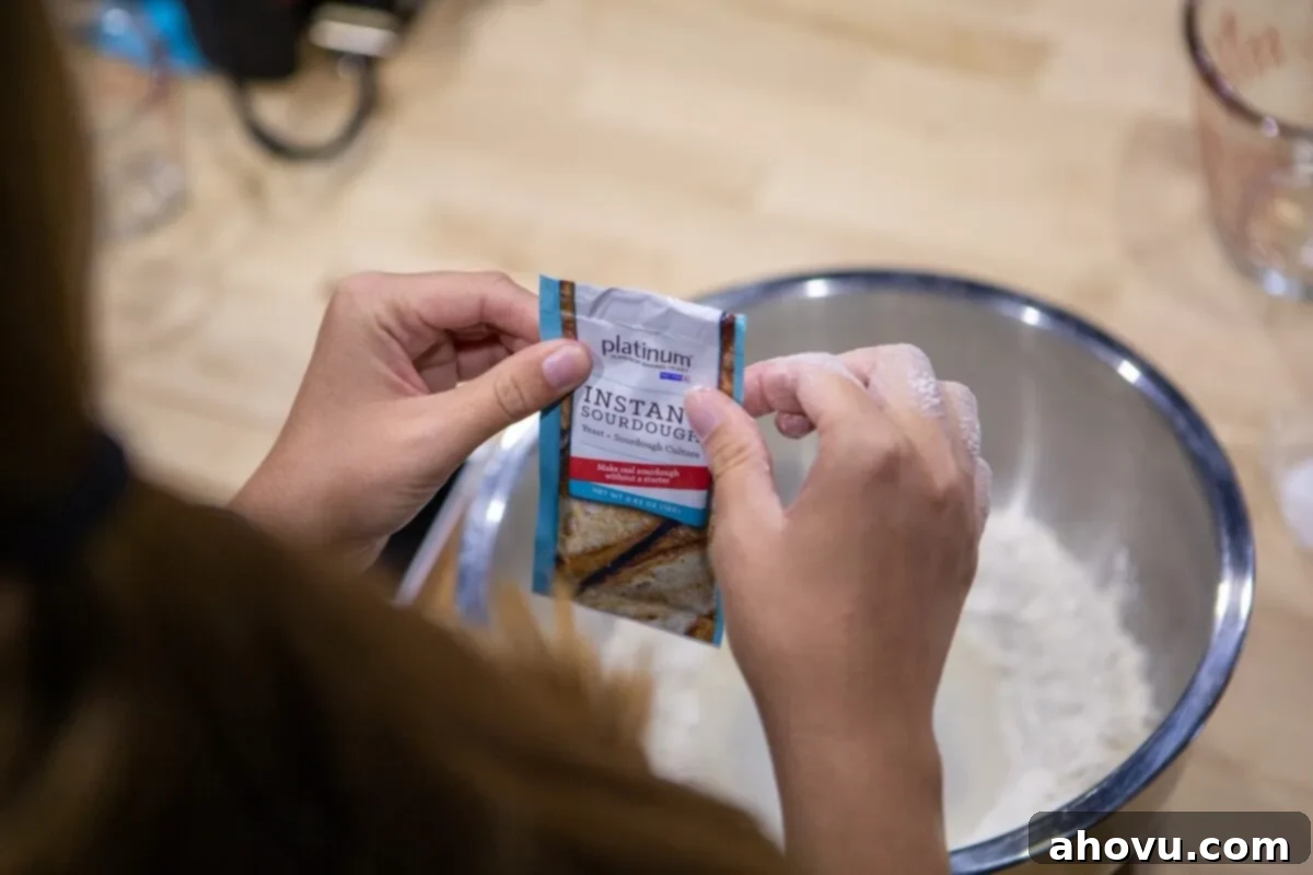 A picture of a person holding a packet of yeast over a bowl of flour.