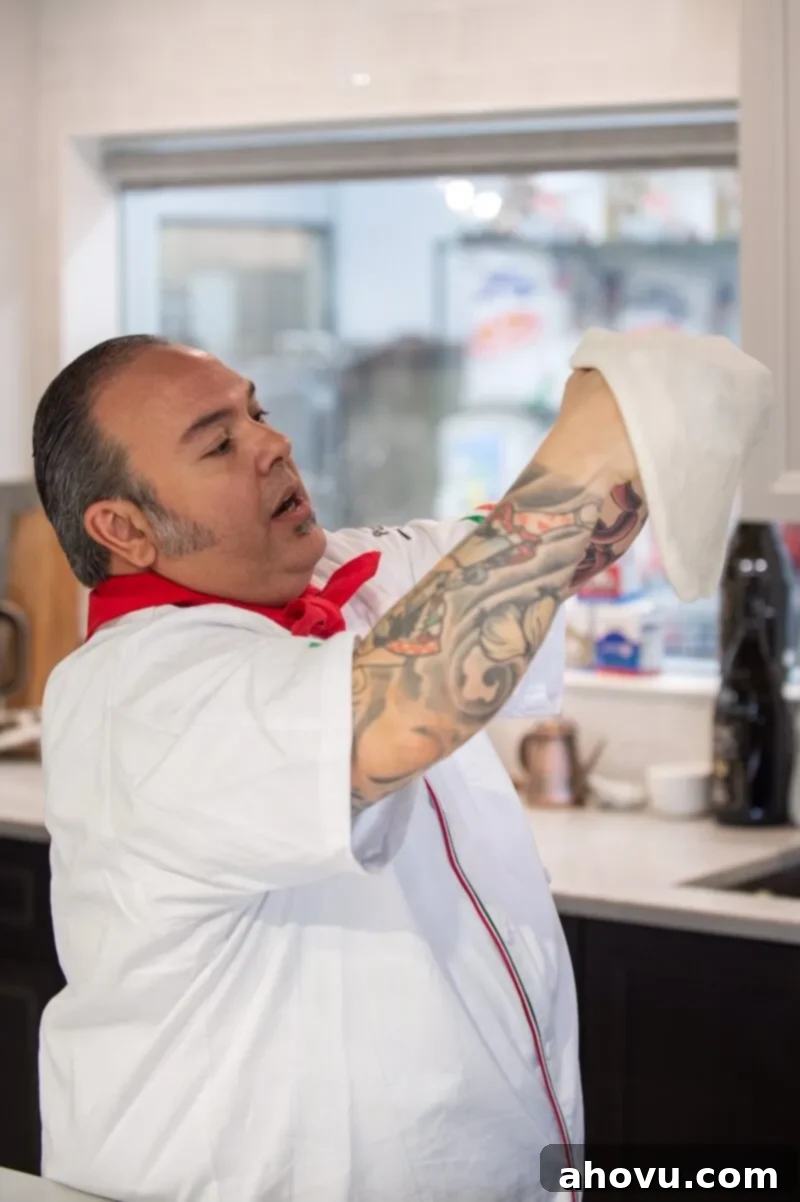 A picture of a chef showing how to stretch pizza dough.