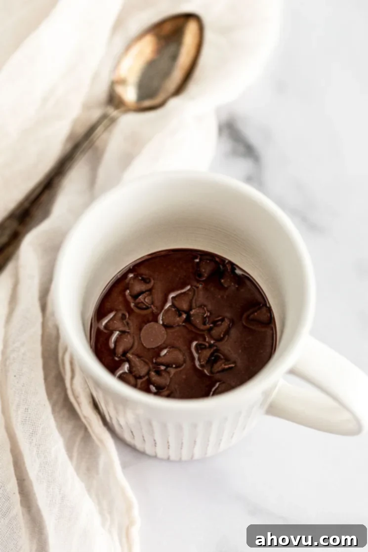 A pristine white mug filled with smooth, dark chocolate mug cake batter, perfectly mixed and ready for its microwave transformation.