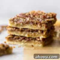 A stack of three pecan pie bars on brown parchment paper.