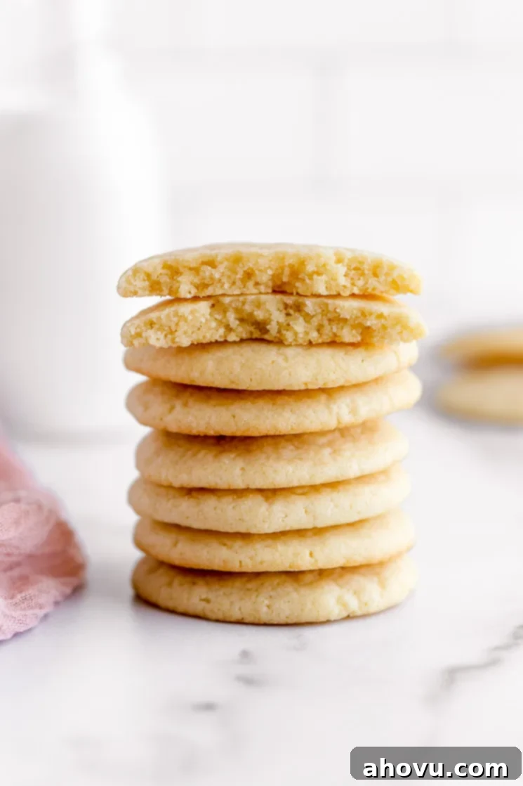 A tempting stack of homemade soft and chewy sugar cookies on an elegant marble surface, showcasing their delicious interior texture with a broken cookie on top.