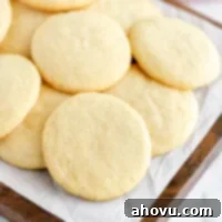 A stack of soft and chewy homemade sugar cookies on a rustic wooden board.