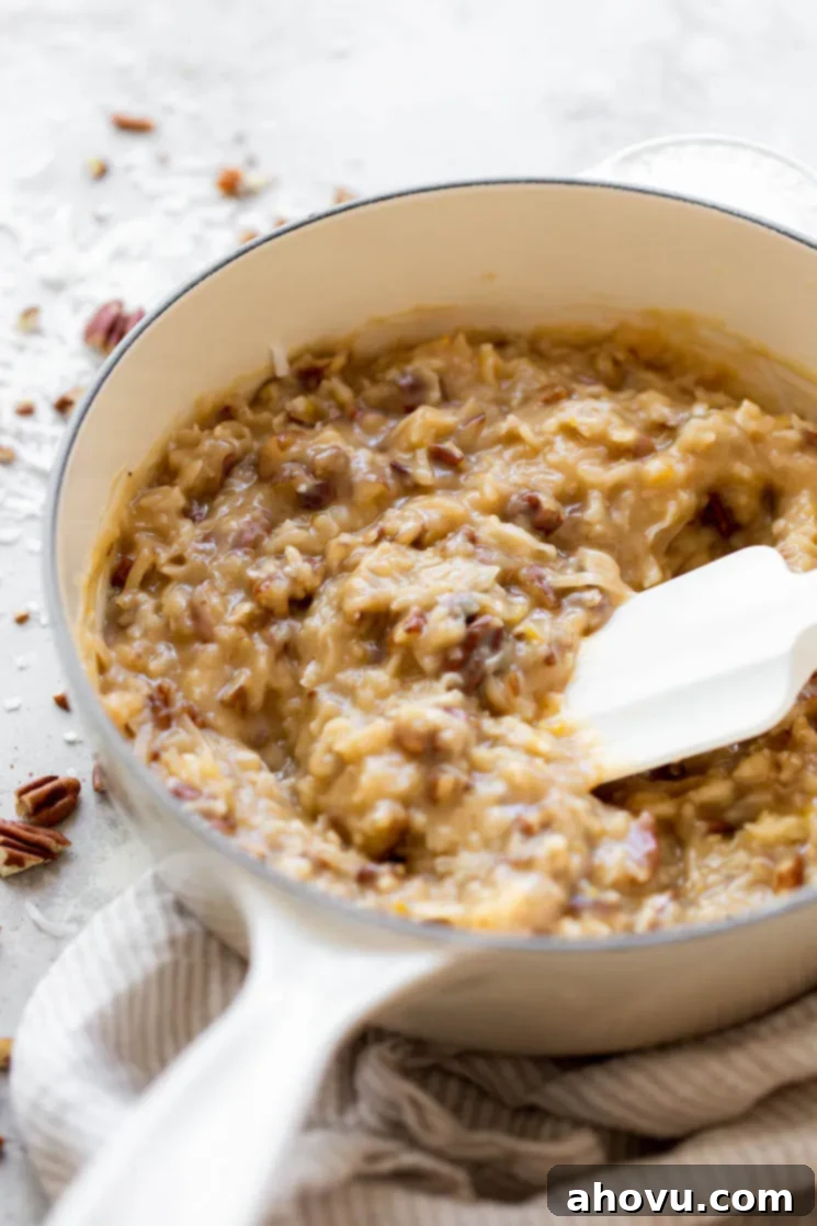 Coconut Pecan Chocolate Dream 4 A pristine white pot filled with a creamy, rich homemade coconut pecan frosting, ready to be spread.
