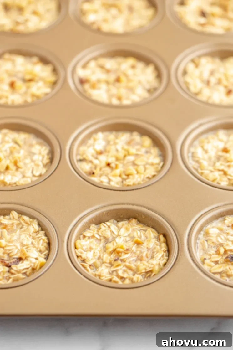 A copper colored muffin pan filled with the banana oatmeal mixture, ready for baking in the oven.