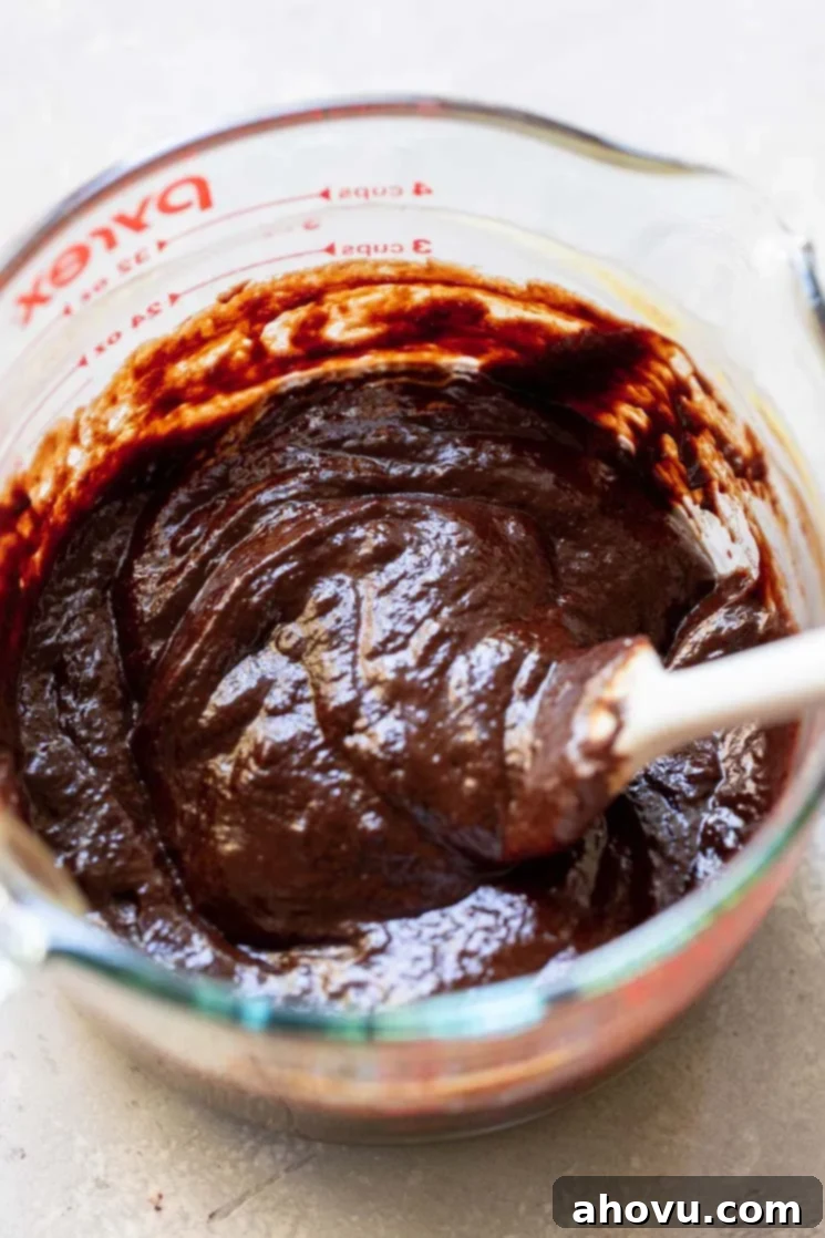 A glass mixing bowl with the egg and chocolate mixture being combined.