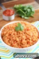 A top-down shot of a bowl of fluffy, orange-tinted Mexican Rice, garnished with a sprinkle of fresh cilantro.