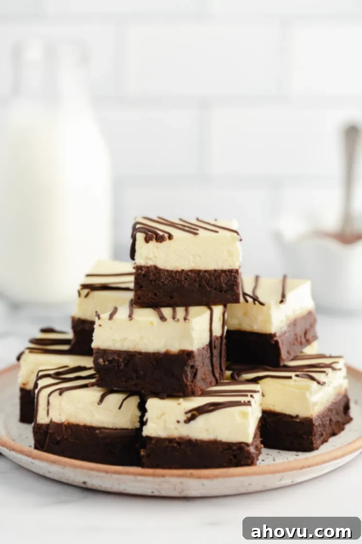 A stack of cheesecake brownies drizzled with chocolate on a rustic clay plate.