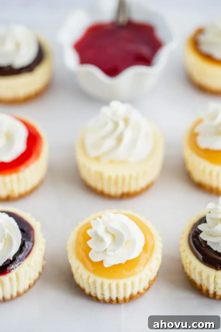 A piece of parchment paper lined with mini cheesecakes topped with different toppings and whipped cream.
