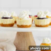 Several mini cheesecakes with different toppings on a marble cake stand.