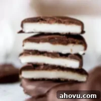 A stack of homemade peppermint patties cut in half to show the layers of creamy white peppermint and dark chocolate.