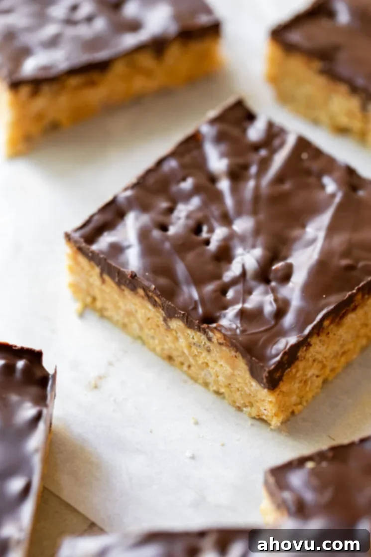 Classic Scotcheroos 5 A finished Scotcheroo bar that has been cut out, showcasing its distinct layers of crispy peanut butter base and the smooth chocolate butterscotch topping on a piece of parchment paper.