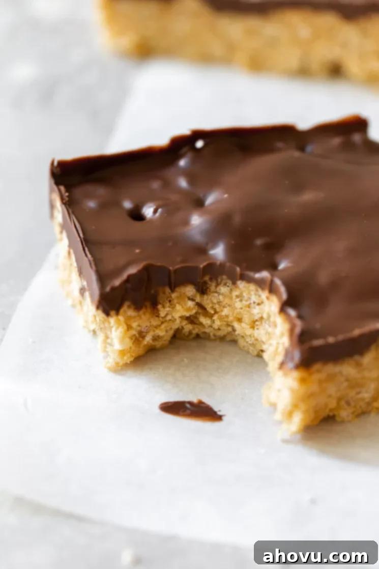 Classic Scotcheroos 6 A single Scotcheroo bar on parchment paper with a bite taken out, showing the crisp rice cereal base and the smooth, firm chocolate butterscotch topping.