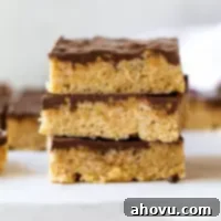 Classic Scotcheroos 7 A stack of three scotcheroos with more in the background, showing their peanut butter base and chocolate butterscotch topping.