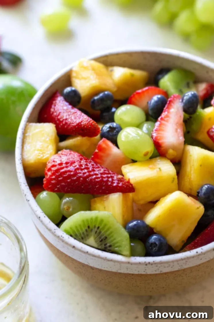 A rustic clay bowl filled with fresh fruit salad, garnished with mint leaves, ready to be served.