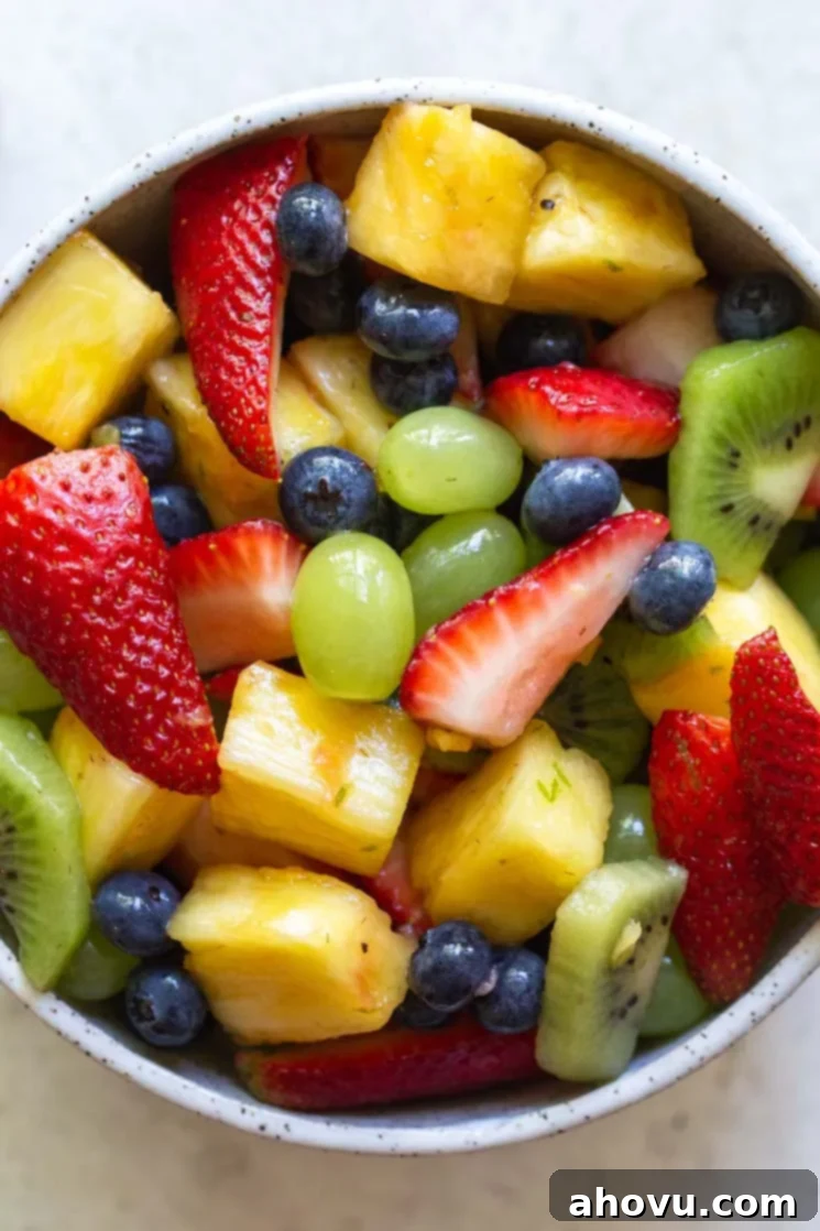 A captivating close-up image of the vibrant fruit salad, beautifully arranged in a rustic clay bowl, highlighting the fresh textures and juicy colors of each fruit piece, inviting a taste.