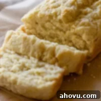 A loaf of beer bread sliced on a piece of parchment paper.