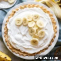 An overhead picture of a finished banana cream pie with extra banana slices on top of the whipped cream.