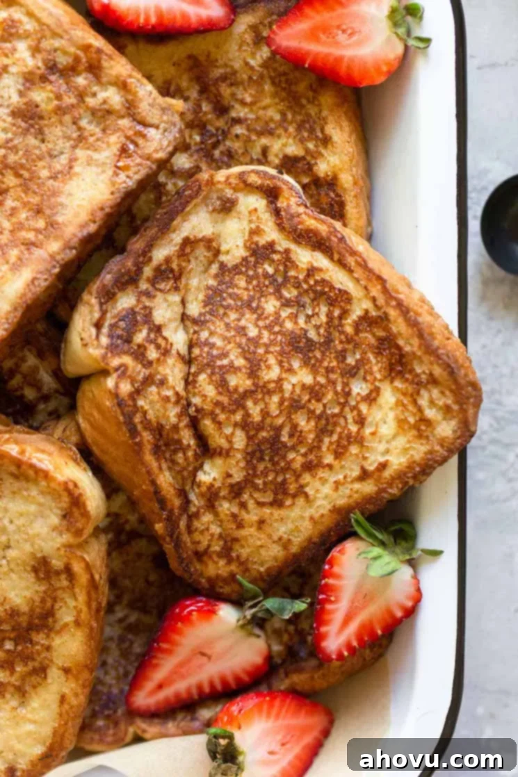 Fluffy French Toast Perfection 6 A close up image of French toast in a baking pan topped with halved strawberries.