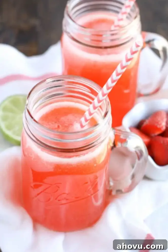 Refreshing Homemade Strawberry Limeade in a glass pitcher with fresh strawberries and lime slices