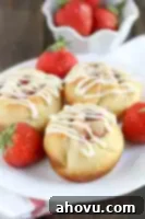 Luscious Strawberry Swirls 5 Three strawberry cinnamon rolls on a white plate.