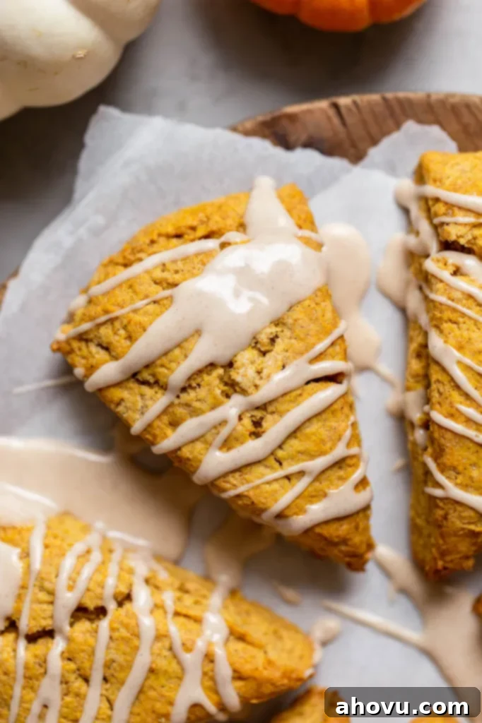 Spiced Pumpkin Scones 4 An overhead shot of a single perfectly baked pumpkin scone, generously topped with a rich maple cinnamon glaze.