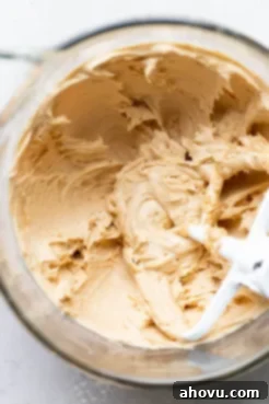 A glass mixing bowl filled with perfectly smooth, thick, and creamy peanut butter frosting, ready for use.