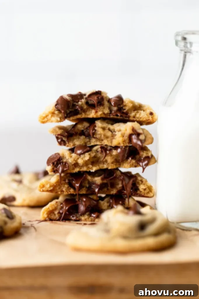 A stack of cookies that have been broken in half showing the texture and melty chocolate chips.