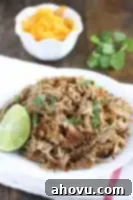 Crispy shredded pork carnitas on a white plate with fresh cilantro.