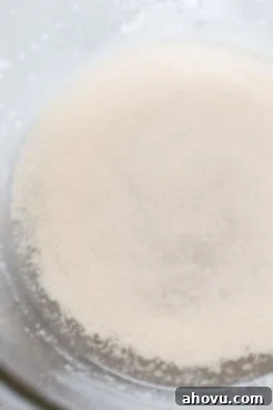 A glass mixing bowl with yeast, sugar, and water.