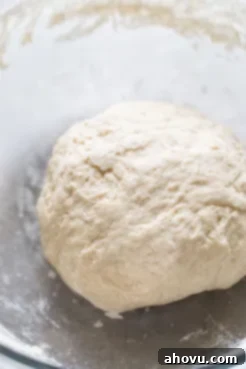 A ball of pretzel dough in a glass mixing bowl.